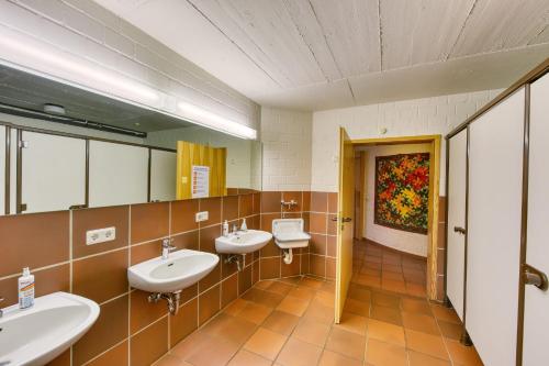 a bathroom with three sinks and two mirrors at Haus Habbinga in Ovelgönne