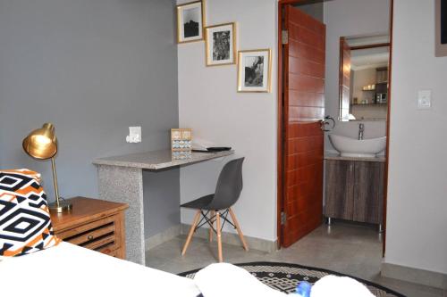 a bedroom with a bed and a desk and a sink at Sleep84 in Dullstroom