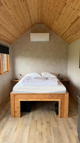 a bed in a room with a wooden ceiling at Tinyhouse Giethoorn in Giethoorn
