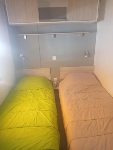 two beds in a small room with yellow sheets at mobil-home FONTAINE Jeremie in Canet-en-Roussillon