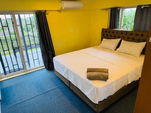 a bedroom with a bed with yellow walls and windows at A1 Apartments in Suva