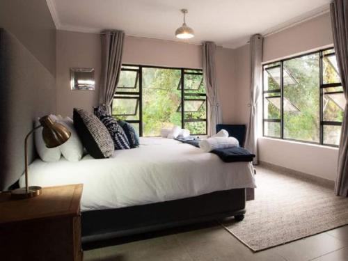 a bedroom with a large white bed with windows at Sleep84 in Dullstroom