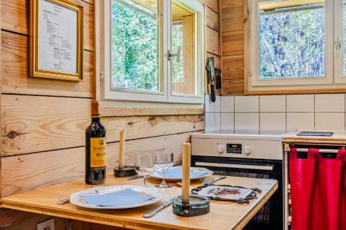 a kitchen with a table with plates and a bottle of wine at La palombière in Saint-Symphorien