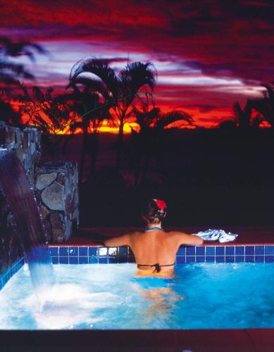 a man in a swimming pool with a sunset at Taveuni Island Resort & Spa in Matei