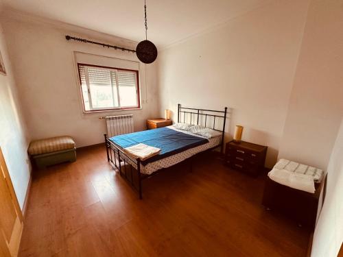 a bedroom with a bed and a window and wooden floors at Gama Barros 22 in Charneca
