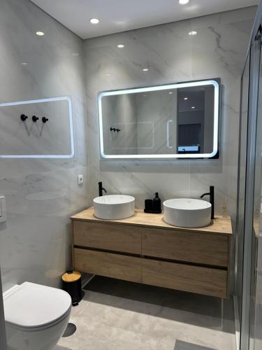 a bathroom with two sinks and a toilet and a mirror at Premium T1 - Sea & Coast in Espinho