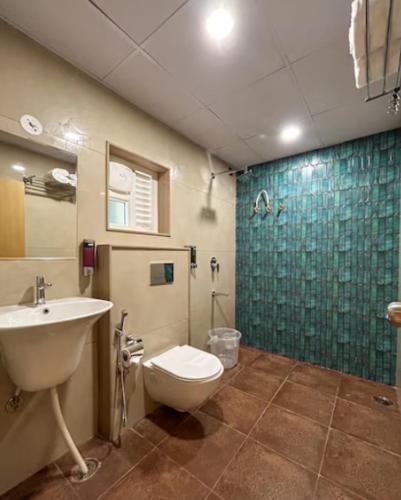 a bathroom with a toilet and a sink and a shower at Hotel Orelio - Airport Hotel in Bangalore