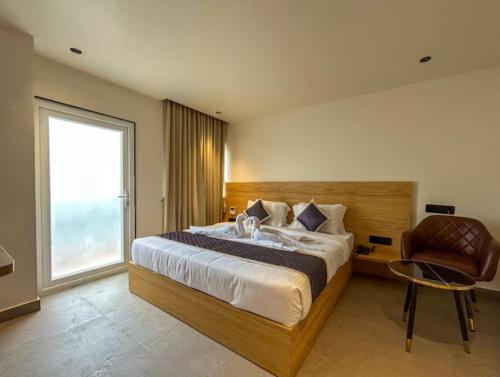 a bedroom with a large bed and a chair at Hotel Orelio - Airport Hotel in Bangalore