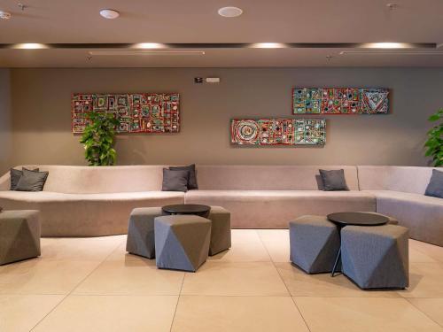 a waiting room with a large couch and stools at Novotel Curitiba Batel in Curitiba