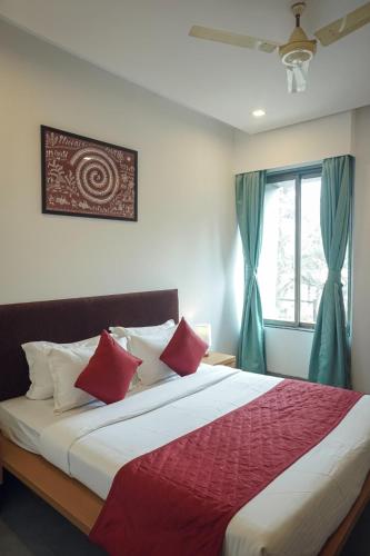 a bedroom with a bed with red pillows and a window at Hotel Paradise in Chākan