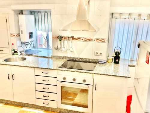 a white kitchen with a sink and a stove at El Rincón de Salsipuedes in Cudillero