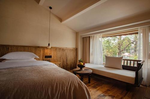 a bedroom with a bed and a window with a bench at Dali Jiwu Hotel in Dali