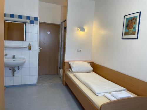 a small bathroom with a bed and a sink at Gasthof Kirchberger in Fürth