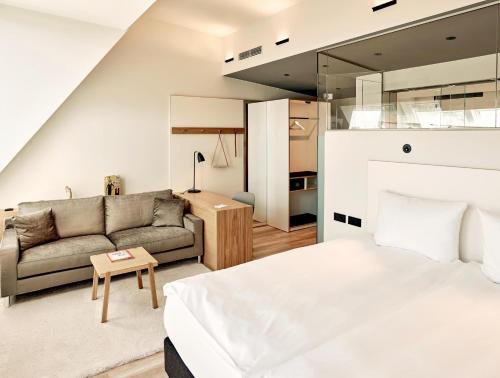 a bedroom with a bed and a couch at Schwabinger Wahrheit by Geisel in Munich