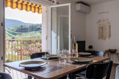 a dining room table with wine glasses and a window at A deux pas de la plage de sable in Le Pradet