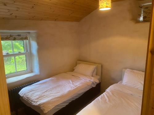 two beds in a small room with a window at The Thatched Cottage in Cork