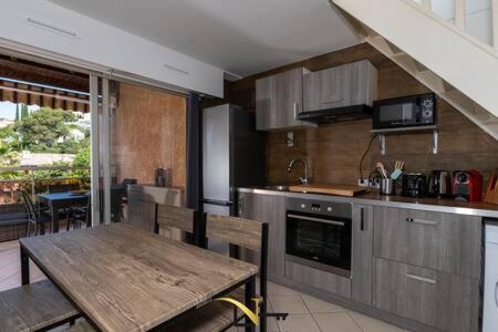 a kitchen with a wooden table and a dining room at Cozy duplexterrace barbecue pool beach on foot in Le Pradet