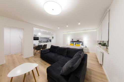 a living room with a black couch and a bedroom at Apartamenty MISTRAL in Karpacz