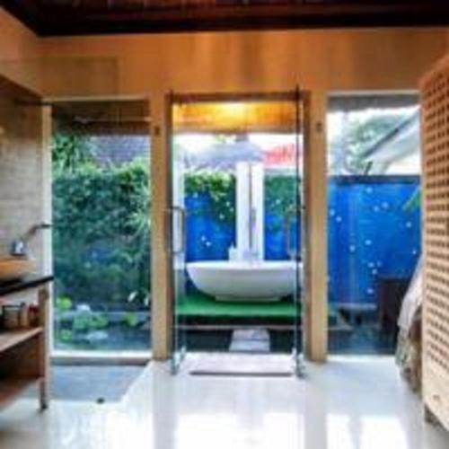 a bathroom with a glass door with a bath tub at Bamboo Moon Villas in Sanur