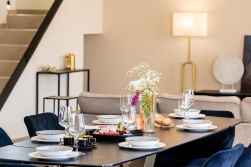 a table with plates and glasses and a vase of flowers at Villa Monégasque elegance & Exclusive seaside getaway in Sérignan