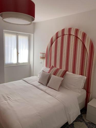 a bedroom with a large white bed with a striped headboard at CasaFiumicello in Maratea