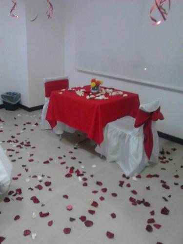 a table with a red table cloth and roses on the floor at Hotel Pinares Plaza in Pereira