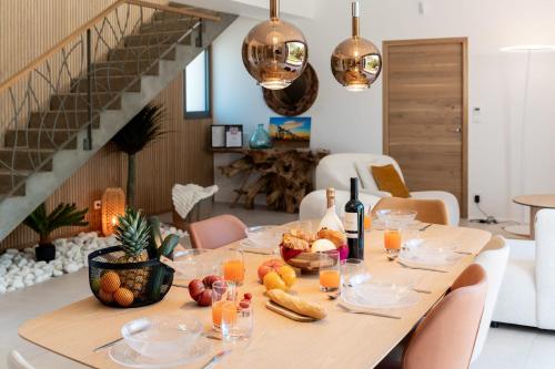 a table with a bunch of fruit and wine bottles at Villa Amphitrite Share beach & happiness in Le Grau-dʼAgde
