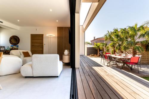 an open living room with a deck with a table and chairs at Villa Amphitrite Share beach & happiness in Le Grau-dʼAgde