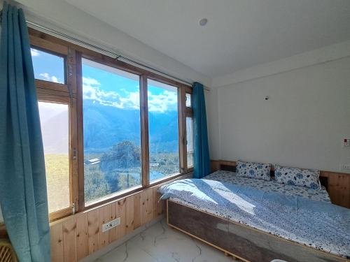 a bedroom with a bed and a large window at Nashala View Homestay in Nagar