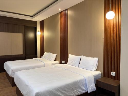 two beds in a hotel room with white sheets at Altha Stay Cokro in Ngabean
