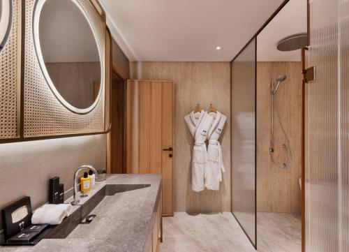 a bathroom with a shower and a sink and a mirror at The Setai Tel Aviv, a Member of the leading hotels of the world in Tel Aviv
