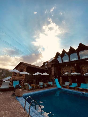 a swimming pool with chairs and umbrellas at Nebesa Hotel EZ in Chimgan