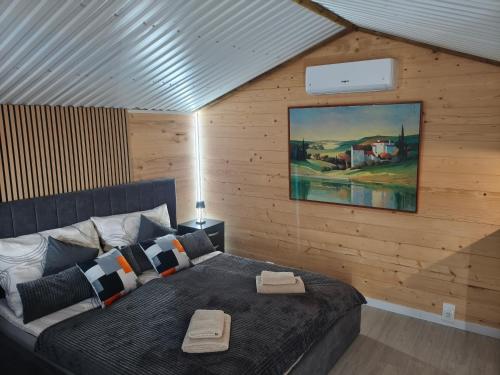 a bedroom with a bed and a painting on the wall at Fenyőházak in Buzsák