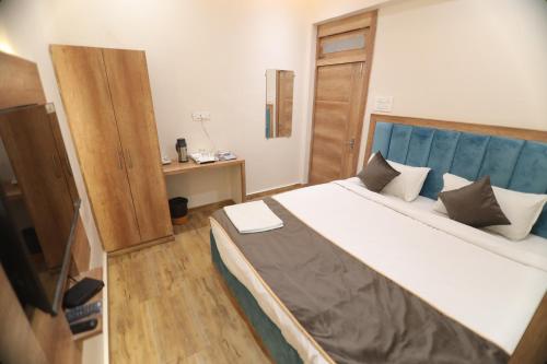a bedroom with a large bed with a blue headboard at Bless Inn in Prayagraj