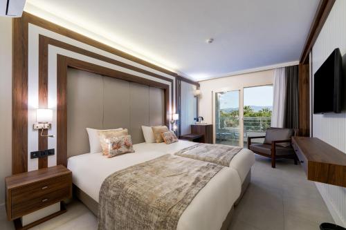 a hotel room with a large bed and a television at Batıhan Beach Resort & Spa in Kuşadası