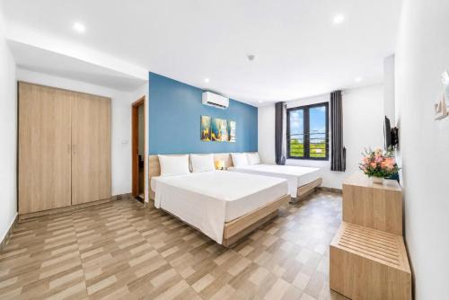 a bedroom with two beds and a blue wall at Cat Ba Violet Hotel and Apartment in Cat Ba