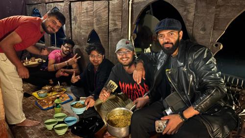 a group of men posing for a picture with food at Heritage hut in Vashisht