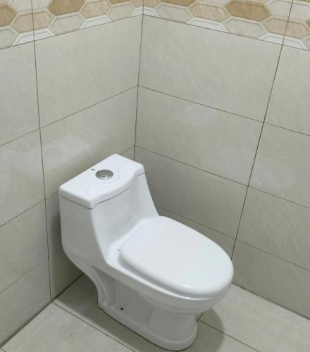 a bathroom with a white toilet in a tiled wall at D'Biru Guest Room in Melur