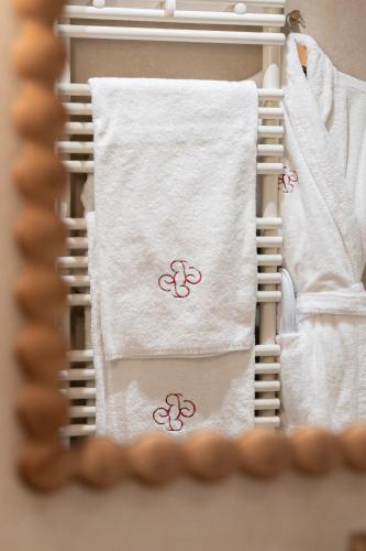a towel rack with white towels with the olympics on it at Chapeau Rouge par William Frachot - Hôtel Espace Bien-être & Restaurant étoilé in Dijon