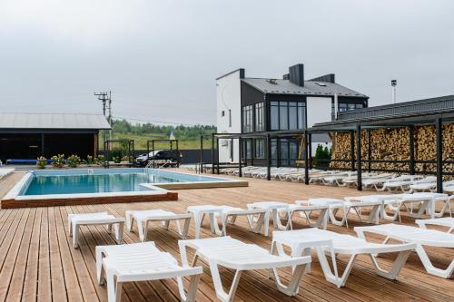 a deck with white lounge chairs and a pool at California Resort and SPA in Novoyavorivsk