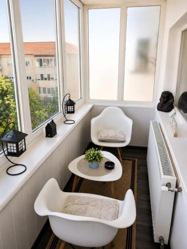 a room with two chairs and a table and windows at Hera Exclusive Stay in Timişoara