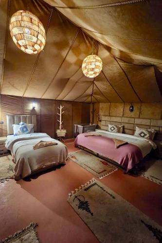 a bedroom with two beds in a tent at Unique Luxury Camp in Merzouga