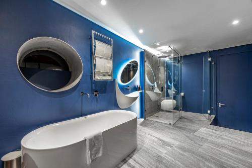 a blue bathroom with a tub and a shower at 17 Marine - Apt 103 - Private Hot Tub & Garden in Hermanus