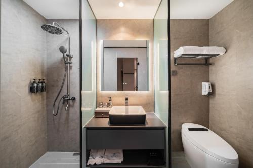 a bathroom with a sink and a toilet and a mirror at 德全m酒店 in Beijing