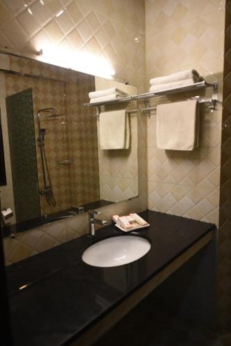 a bathroom with a sink and a shower with towels at Millennium Inn Hotel Naran in Naran