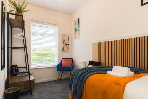 a bedroom with a bed and a chair and a window at Heath Lodge in Stockingford