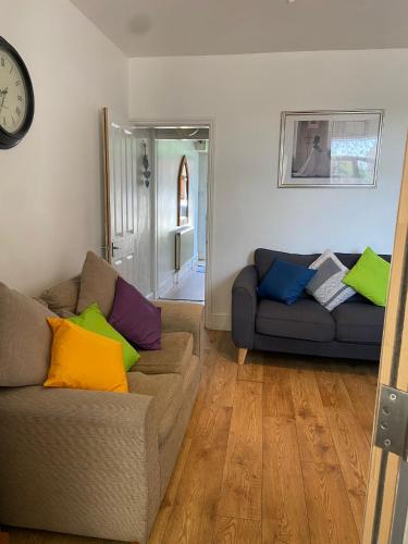 a living room with two couches and a clock at 4 Bedroom House For Corporate Stays in Kettering in Kettering