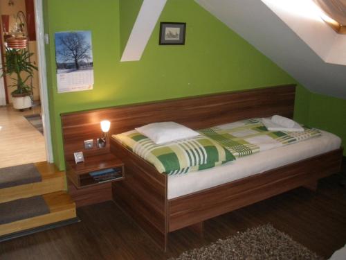 a bedroom with a bed with a green wall at Sopron Eszter Apartman in Sopron
