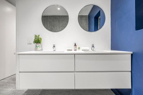 a bathroom with a white sink and two mirrors at 17 Marine - 2 Bedroom - Garden - Apt 104 in Hermanus