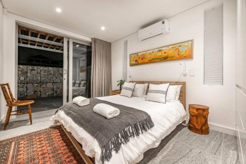 a bedroom with a large bed and a chair at 17 Marine - 2 Bedroom - Garden - Apt 104 in Hermanus